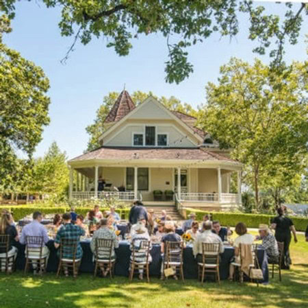 Guests enjoying outdoor event at 2018 Festival Napa Valley with a historic house backdrop.