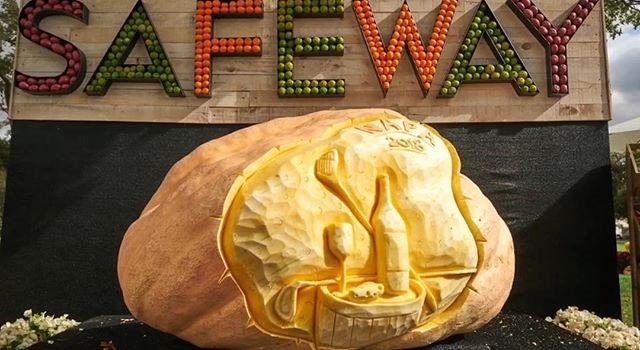 Colorful 'SAFEWAY' sign with a large carved stone sculpture in front at the PGA Safeway Open in Napa.
