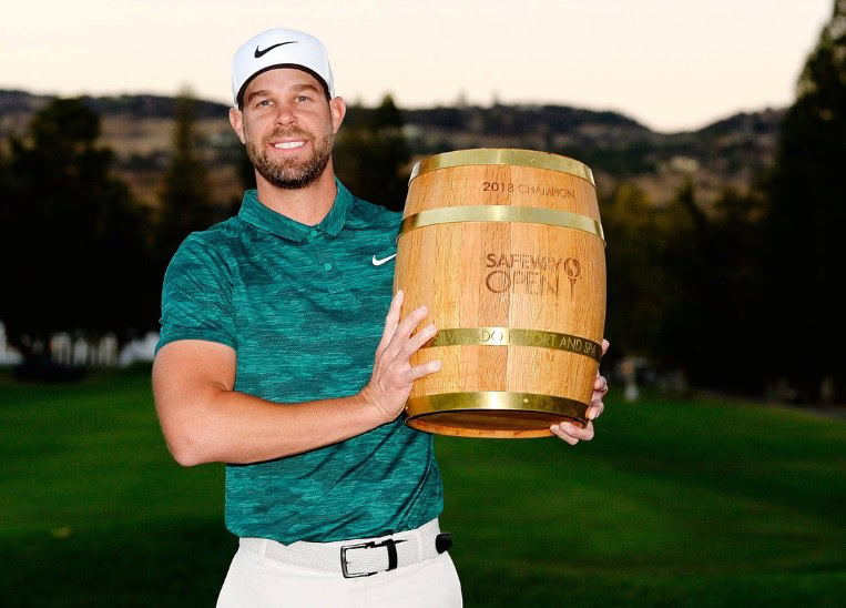 Golf champion holding the 2018 Safeway Open trophy on the golf course.
