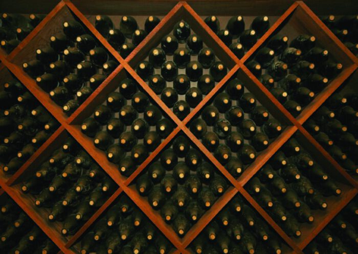 Wine bottles stored in a wooden rack at 90 Plus Wine Club.